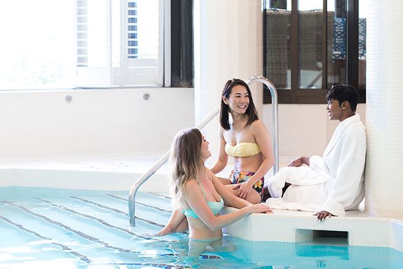 A group lounges by the pool between spa services at Elmwood Spa